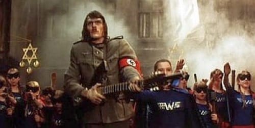 In front of a synagogue a Frankenstein monster with a face that resembles Hitler and wearing a Nazi armband holds a machine gun while surrounded by people wearing superhero-like outfits with a "W" logo for "Wagner."